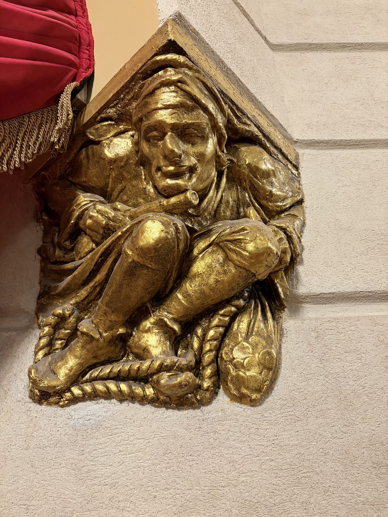 A gilded decorative plaster corbel with a seated figure
